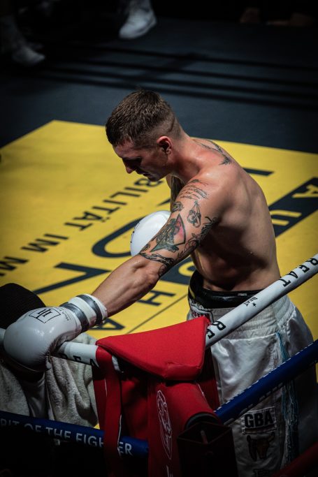 Boxer in der Ecke des Rings, erschöpft mit einem Handtuch und tätowiertem Arm.