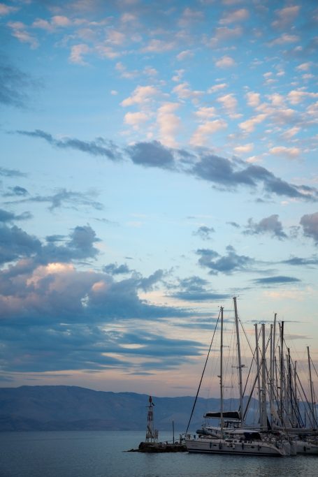 Anleger mit Segelbooten vor einem bewölkten Himmel und sanften Wellen.